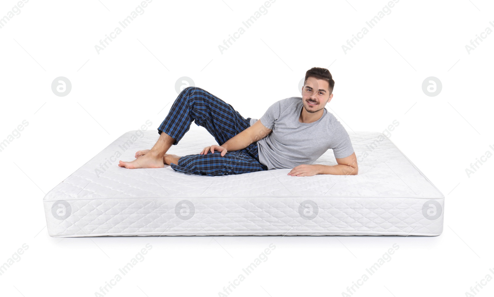 Photo of Young man sitting on mattress against white background