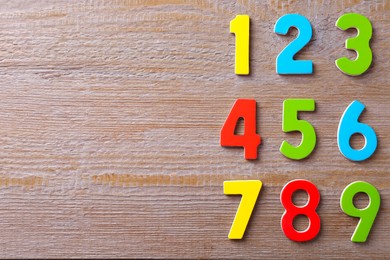 Colorful numbers on wooden table, flat lay. Space for text