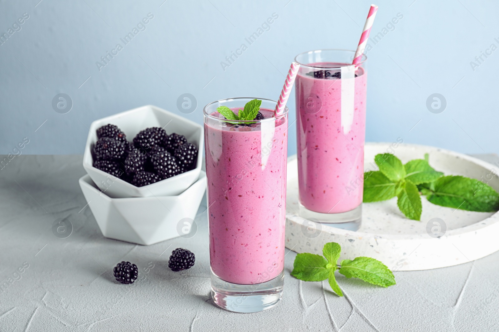 Photo of Delicious blackberry smoothie in glasses on light table