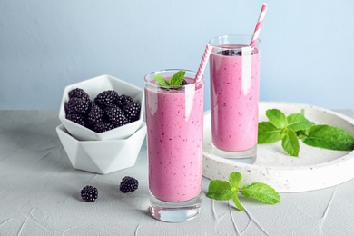 Photo of Delicious blackberry smoothie in glasses on light table