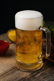 Glass mug with tasty beer on wooden table