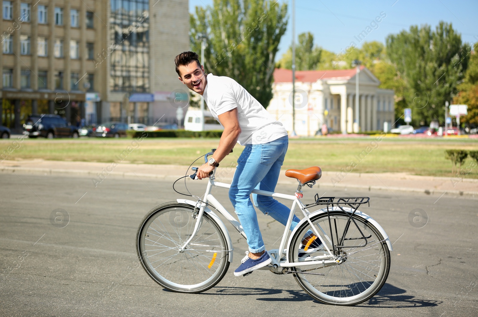 Photo of Handsome young hipster man riding bicycle outdoors