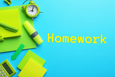 Image of Green school stationery and inscription HOMEWORK on light blue background, flat lay