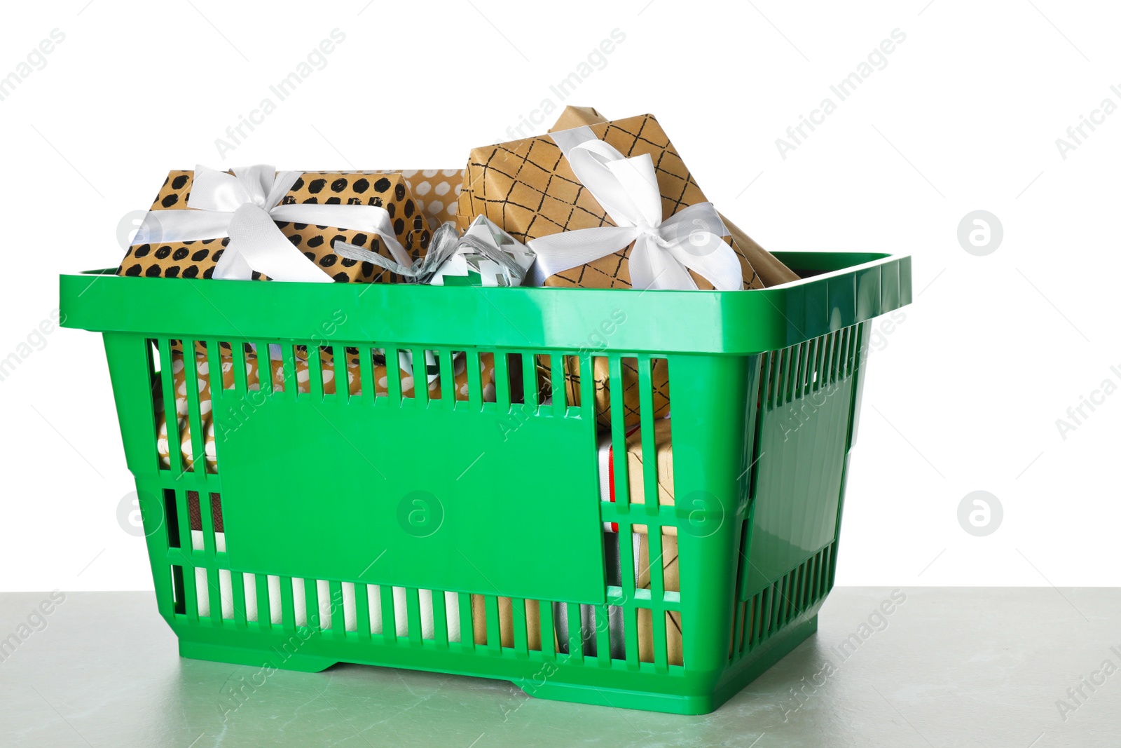 Photo of Shopping basket full of gift boxes on light grey marble table against white background