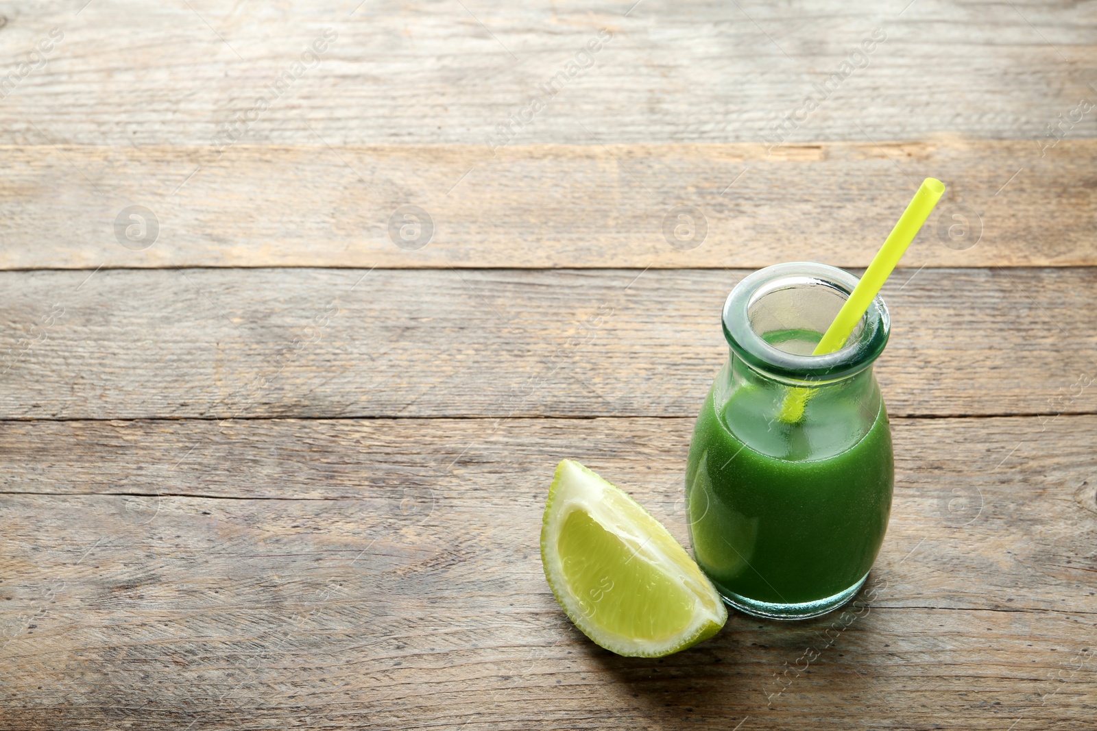 Glass bottle of wheat grass juice with citrus fruit on wooden background. Space for text Photo of Glass bottle of wheat grass juice with citrus fruit on wooden background. Space for text