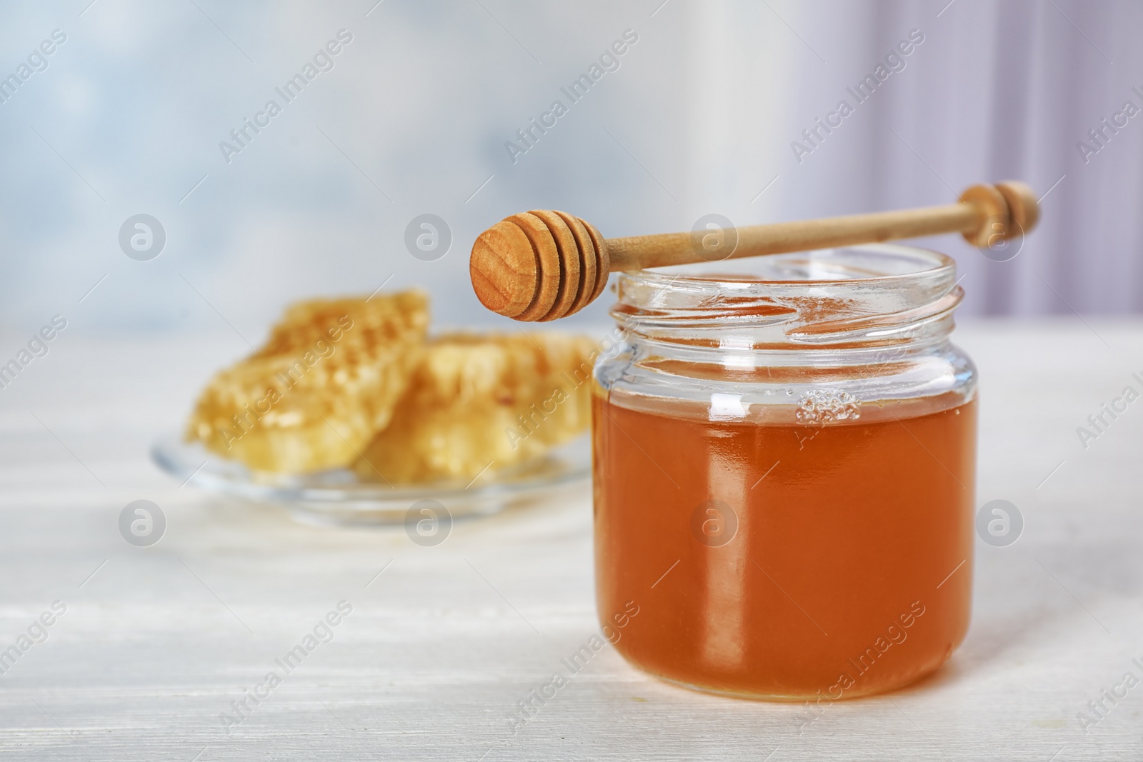 Photo of Jar of honey and dipper on table