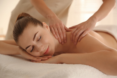 Photo of Young woman receiving shoulder massage in spa salon