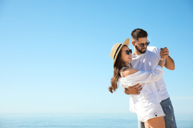 Photo of Happy young couple dancing at beach near sea. Honeymoon trip