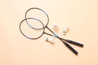 Feather badminton shuttlecocks and rackets on beige background, flat lay