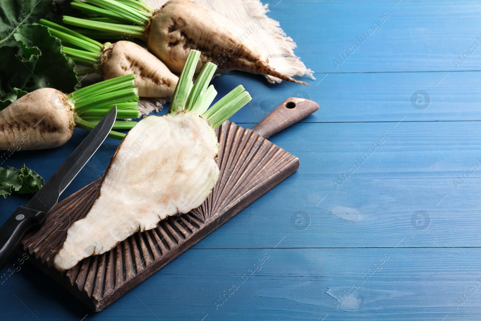 Photo of Whole and cut sugar beets on blue wooden table. Space for text