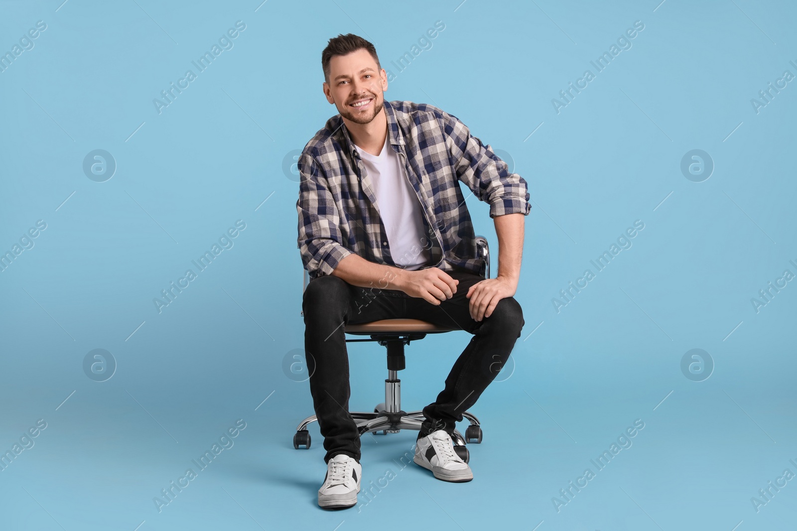 Photo of Handsome man sitting in office chair on light blue background