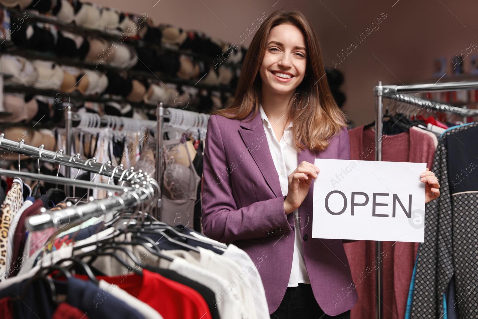 Photo of Young business owner holding OPEN sign in boutique