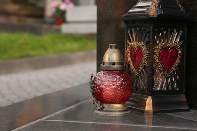 Photo of Different grave lanterns on granite tombstone outdoors, space for text