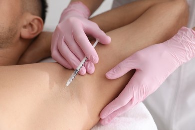 Photo of Cosmetologist injecting man's armpit, closeup. Treatment of hyperhidrosis