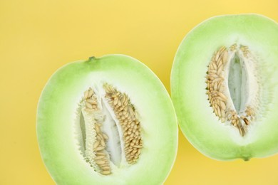 Photo of Halves of fresh ripe honeydew melon on yellow background, flat lay