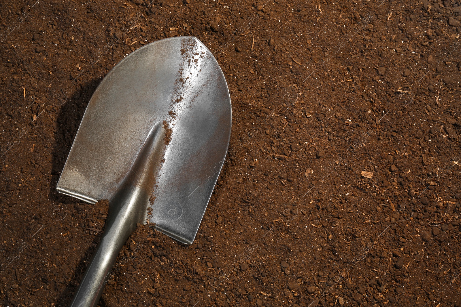 Metal shovel on fertile soil, top view and space for text. Gardening tool Photo of Metal shovel on fertile soil, top view and space for text. Gardening tool