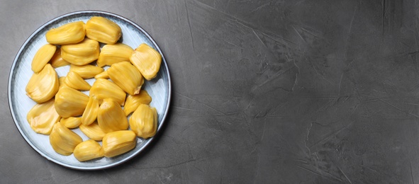 Photo of Delicious exotic jackfruit bulbs on grey table, top view. Space for text