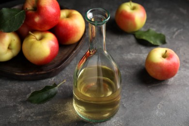 Photo of Natural apple vinegar and fresh fruits on grey table