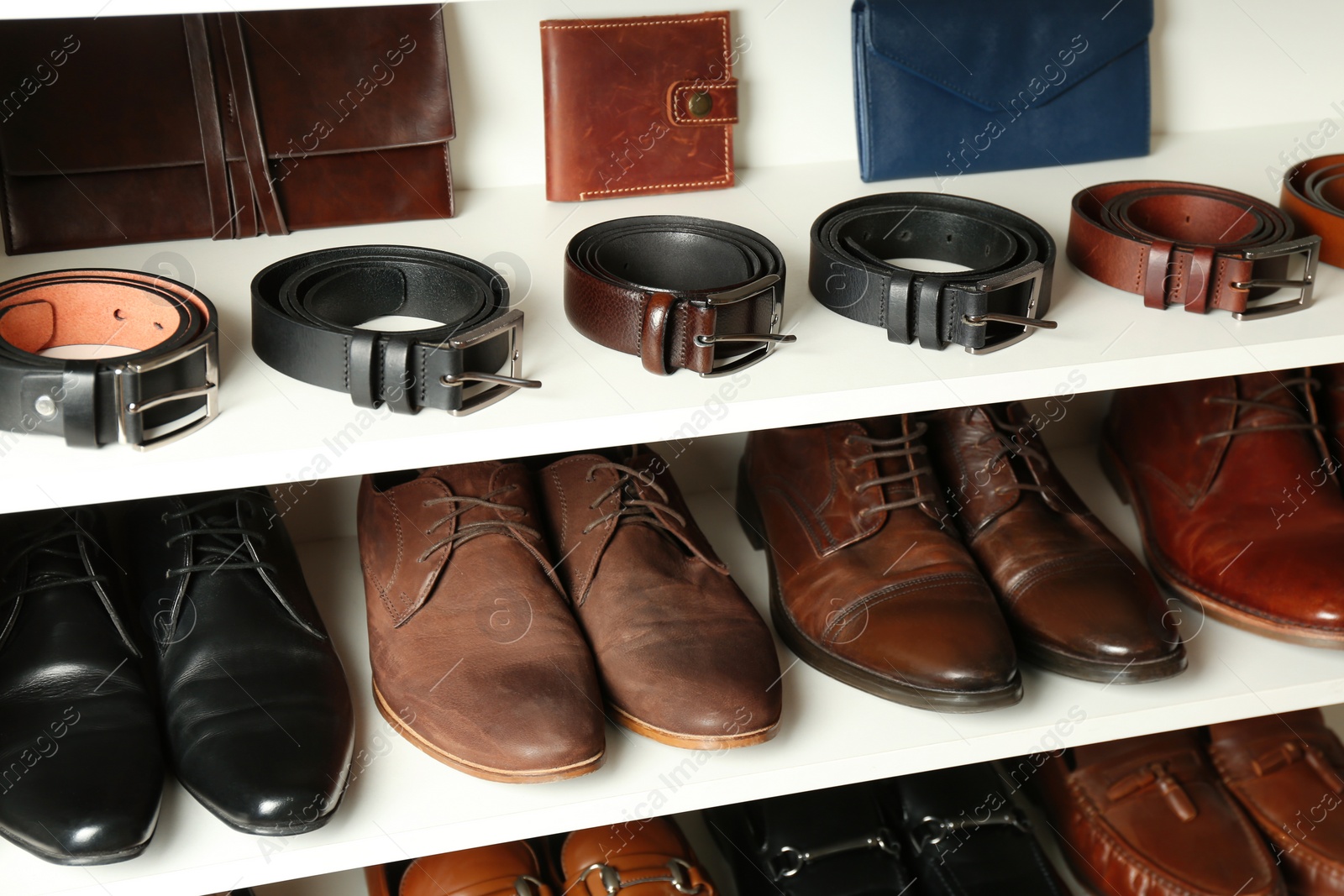 Photo of White shelving unit with different leather shoes and accessories