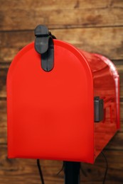 Photo of Closed red letter box against wooden background, closeup