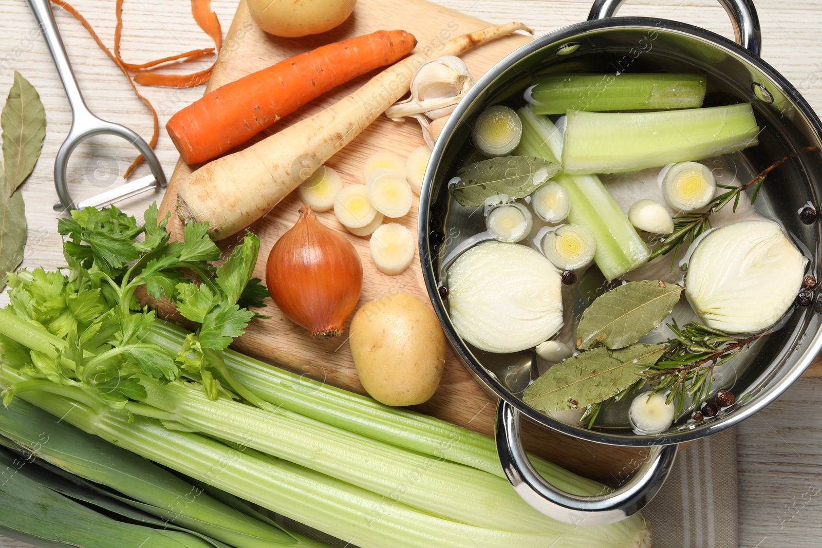 Photo of Pot and different ingredients for cooking tasty bouillon on white wooden table, flat lay