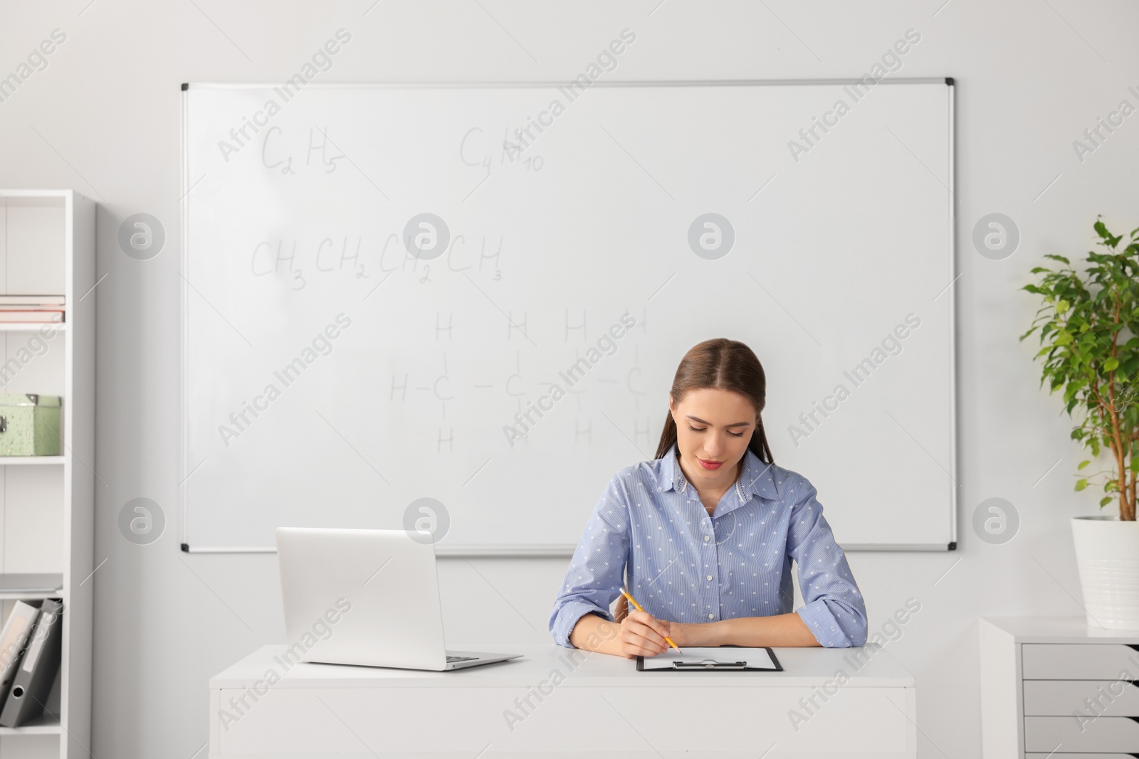 Photo of Young chemistry teacher giving lesson at table in classroom