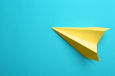 Photo of Yellow paper plane on light blue background, top view. Space for text