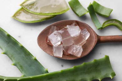 Photo of Aloe vera gel and slices of plant on light table, flat lay