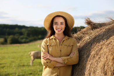 Photo of Smiling woman near hay bale on animal farm. Space for text