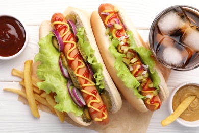 Photo of Delicious hot dogs with lettuce, onion and pickle served on white wooden table, flat lay