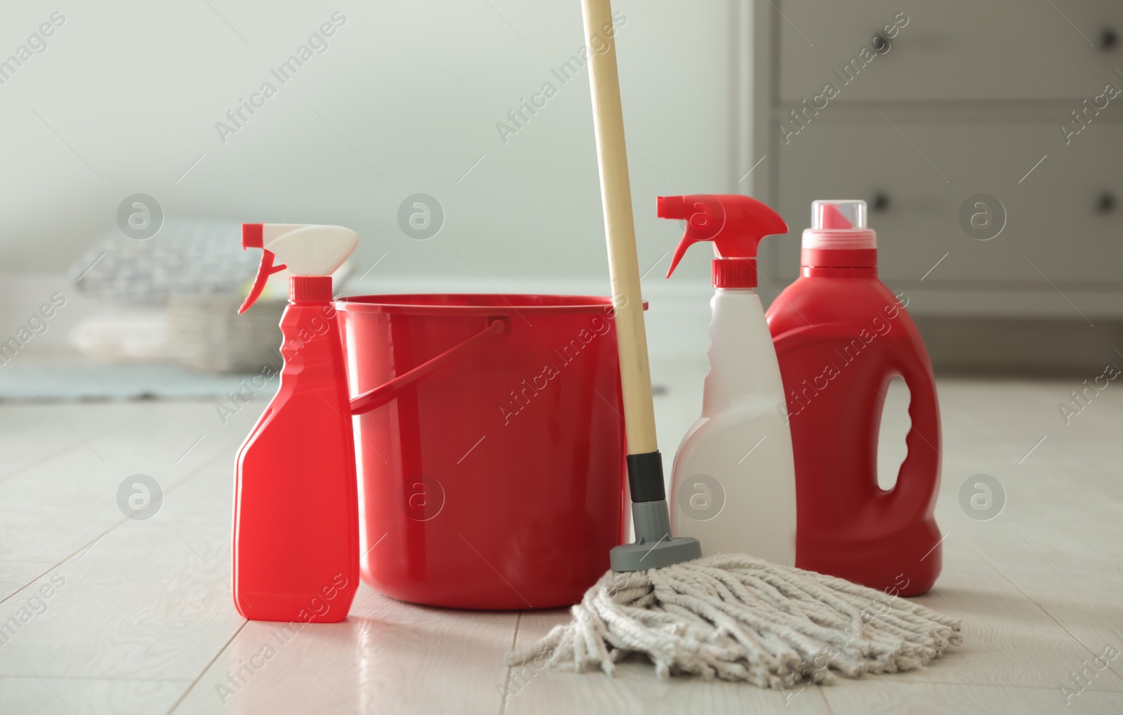 Photo of Bucket, mop and different cleaning products on floor indoors