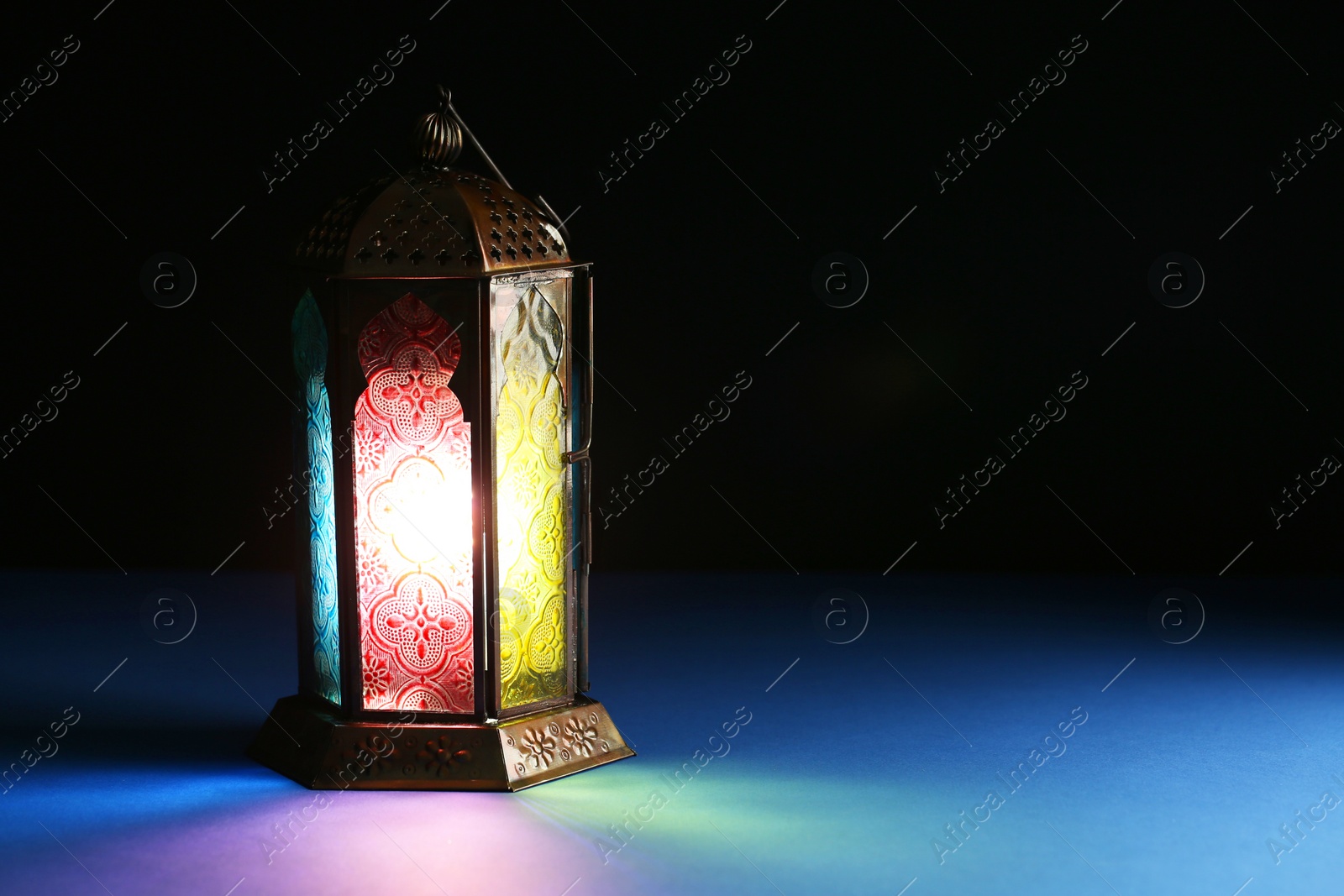 Photo of Decorative Arabic lantern on table against dark background. Space for text