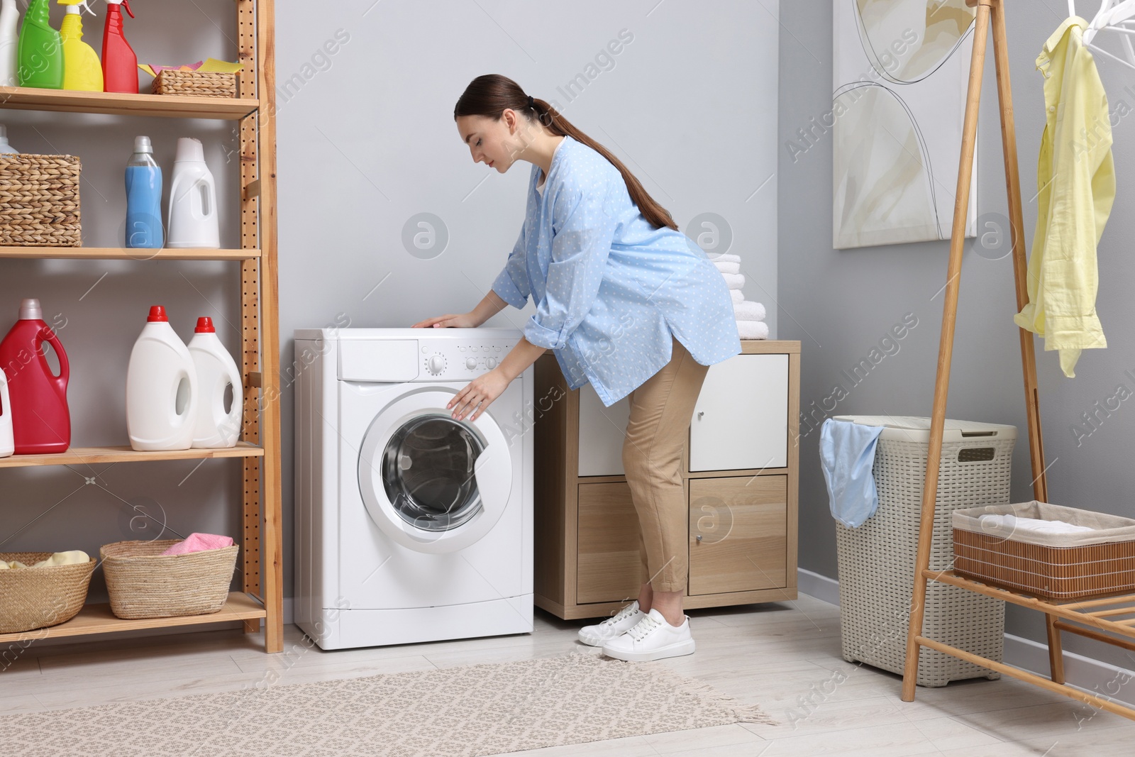 Photo of Beautiful woman near washing machine in laundry room