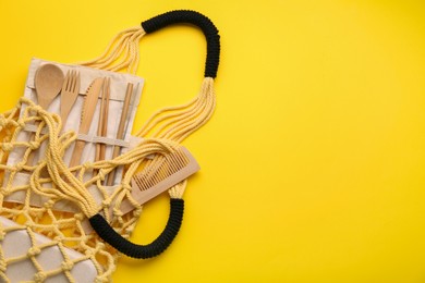 Photo of Fishnet bag with different items on yellow background, top view and space for text. Conscious consumption