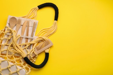 Fishnet bag with different items on yellow background, top view and space for text. Conscious consumption