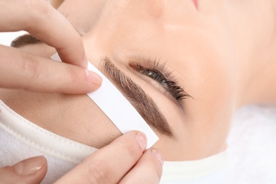 Young woman having professional eyebrow correction procedure in beauty salon