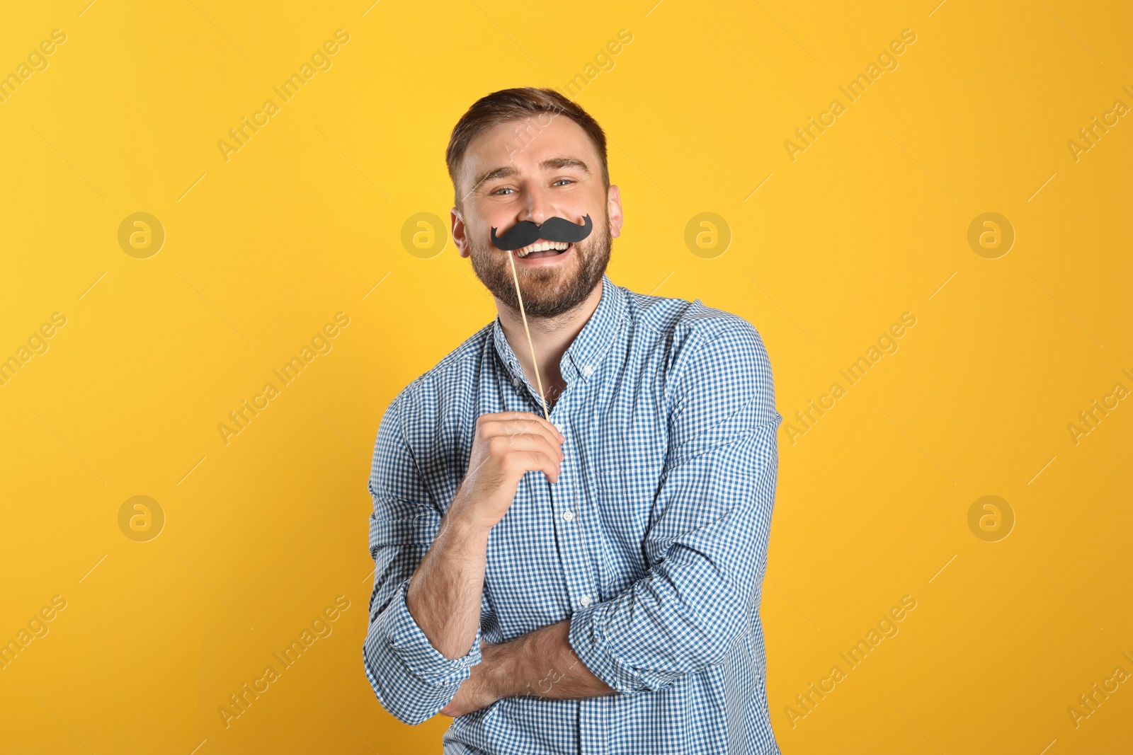 Photo of Funny man with fake mustache on yellow background