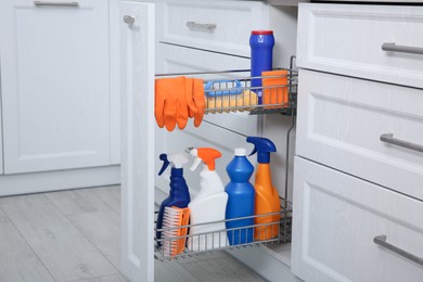 Photo of Open drawer with different cleaning supplies in kitchen