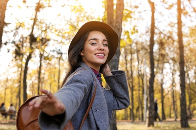 Photo of Young beautiful woman with backpack in park. Autumn walk