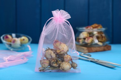 Photo of Scented sachet with dried roses on light blue table