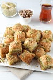 Photo of Delicious fresh baklava with chopped nuts served on white table. Eastern sweets