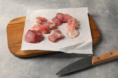 Photo of Paper towel, pieces of meat and knife on grey table