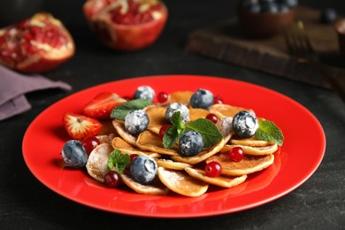 Photo of Cereal pancakes with berries and mint on black table