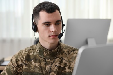 Photo of Military service. Young soldier in headphones working in office