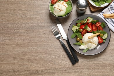 Photo of Delicious burrata salad served on wooden table, flat lay. Space for text