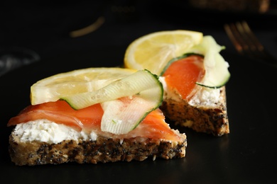 Photo of Delicious bruschettas with salmon on black table, closeup view