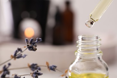 Photo of Dripping of lavender essential oil into bottle, closeup. Space for text