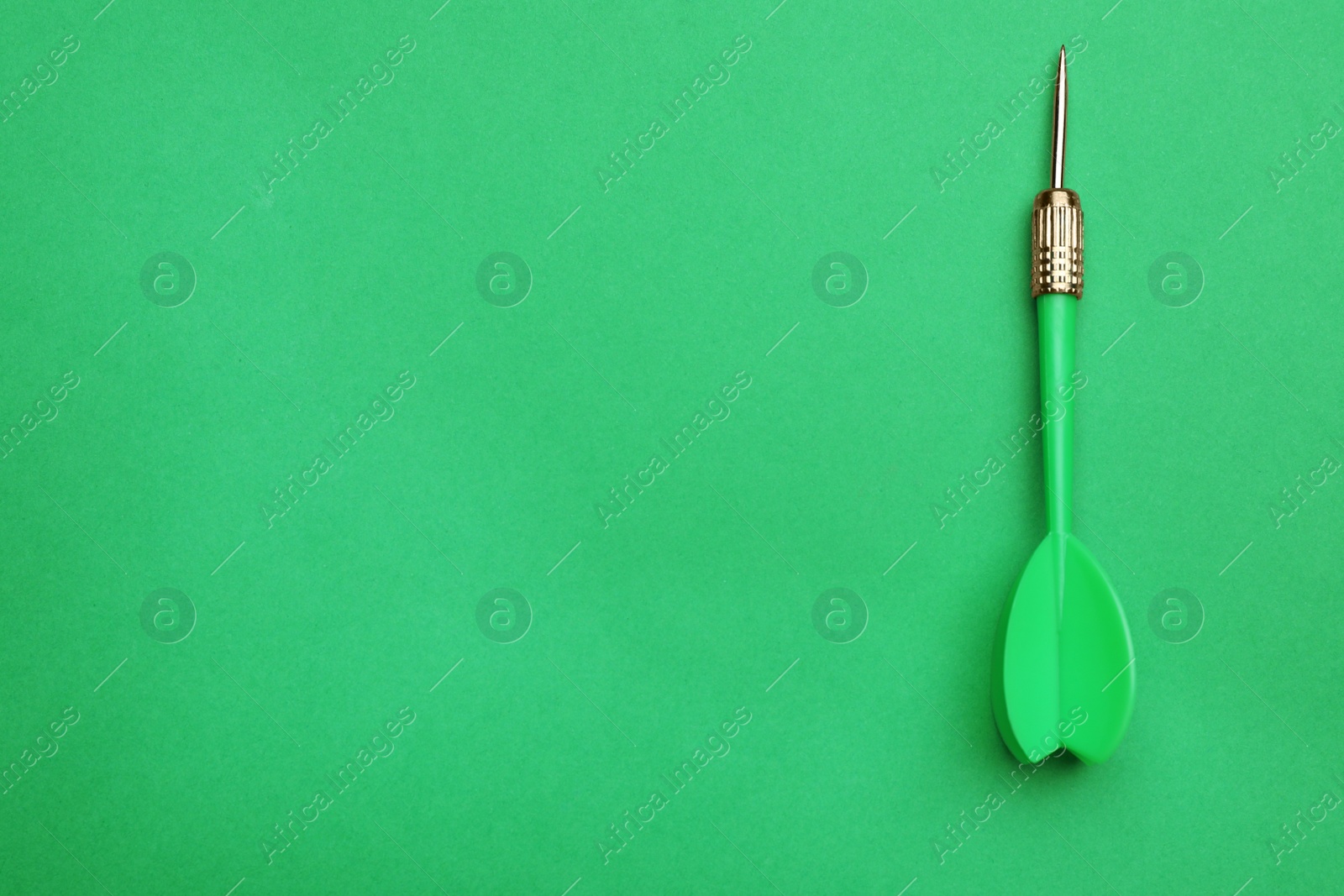 Photo of Plastic dart arrow on green background, top view with space for text