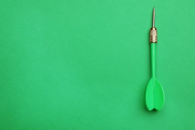 Photo of Plastic dart arrow on green background, top view with space for text