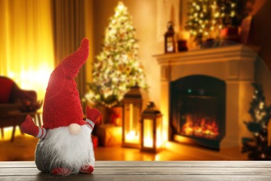 Image of Funny Christmas gnome on wooden table in room with festive decorations. Space for text